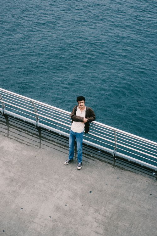 Free Man standing on a pier by the ocean, wearing casual attire. Ideal for lifestyle imagery. Stock Photo