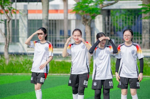 Four young women in soccer uniforms on a field in Hanoi, Vietnam, in daytime.