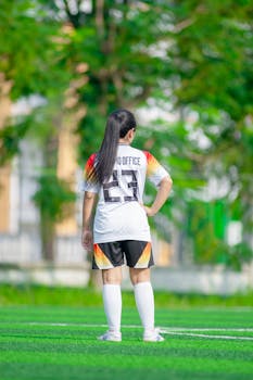 Teen girl in soccer uniform standing on a field in Hà Nội, Việt Nam.