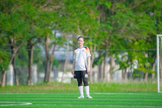 Young woman playing soccer outdoors in Hanoi. Vibrant greens and active lifestyle.