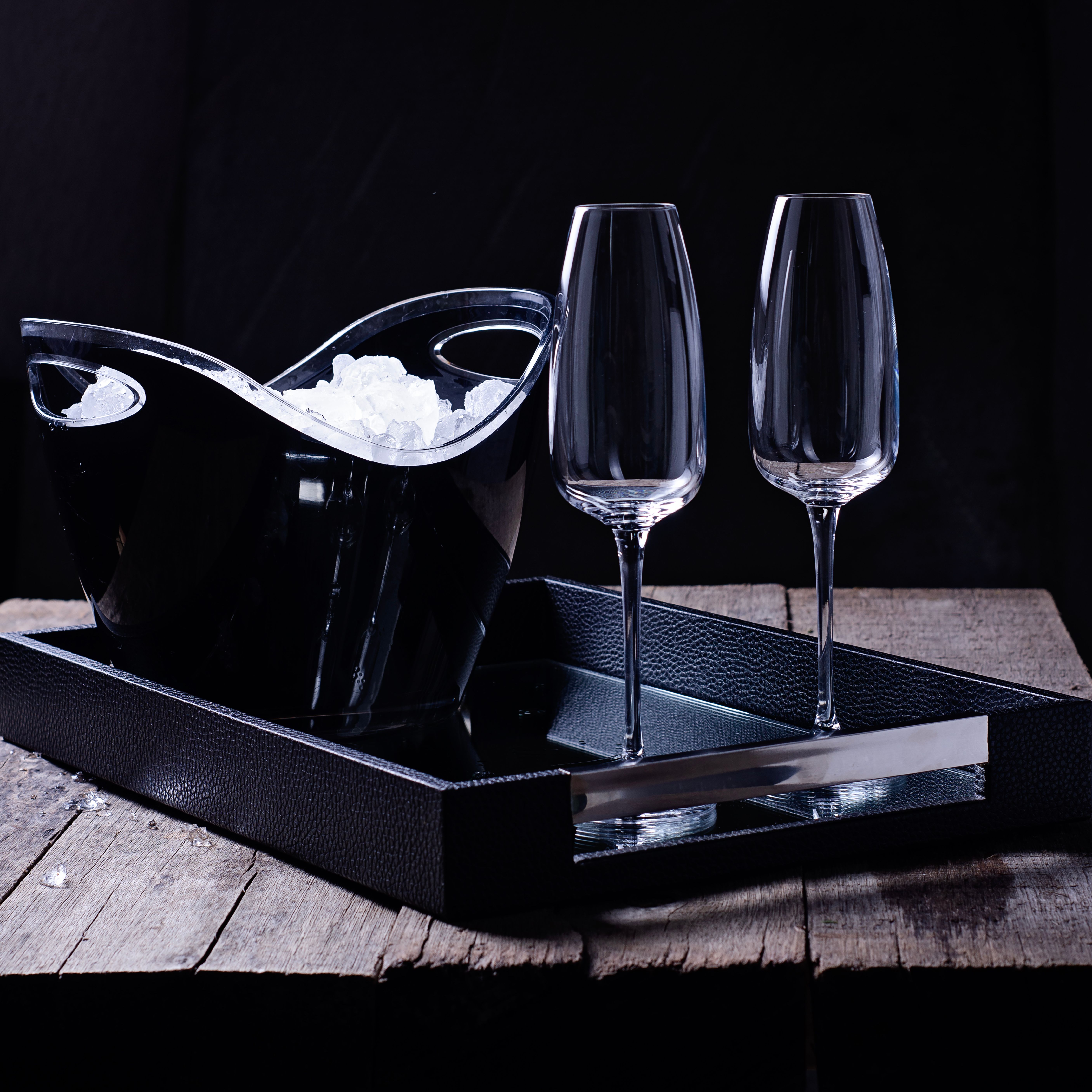 Sophisticated still life featuring an elegant ice bucket and champagne glasses on a rustic table.