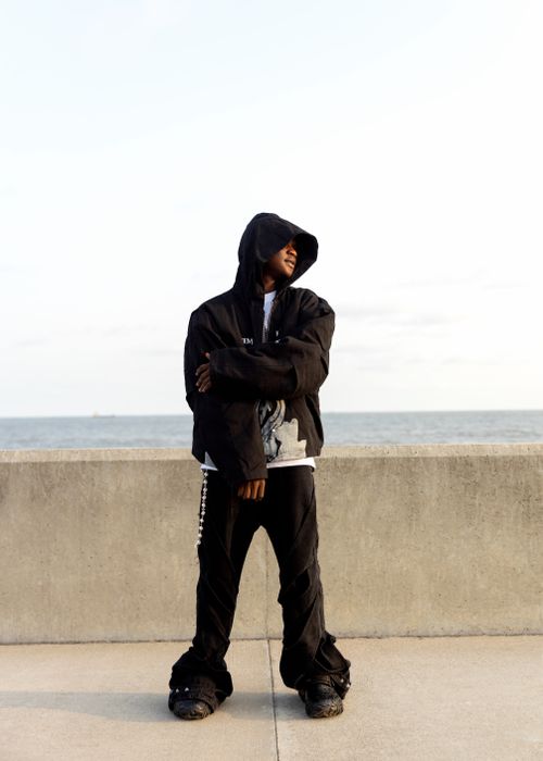 Free Stylish individual in black attire poses confidently by the beach. Stock Photo