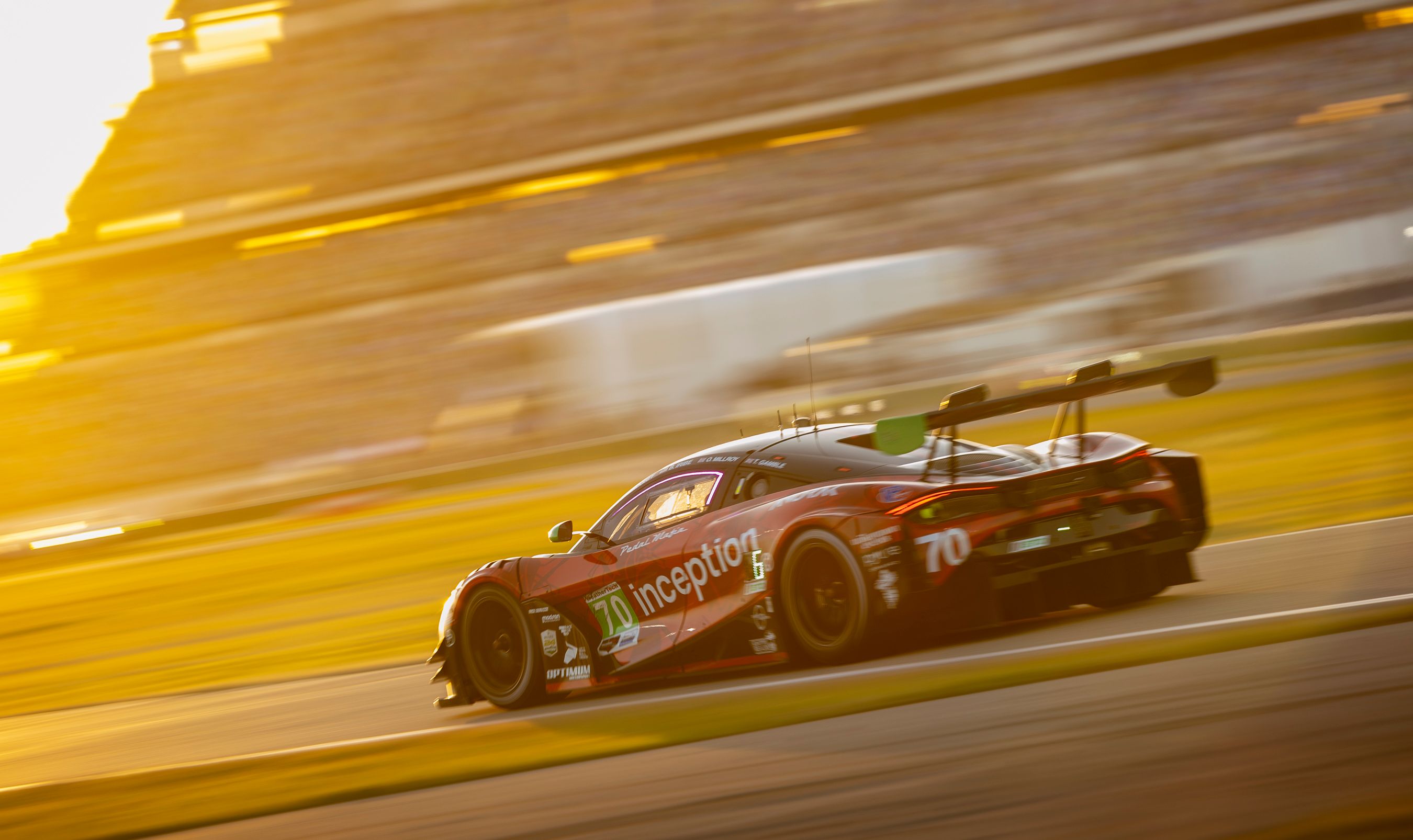 A thrilling auto race car speeding on Daytona Beach track during sunset.