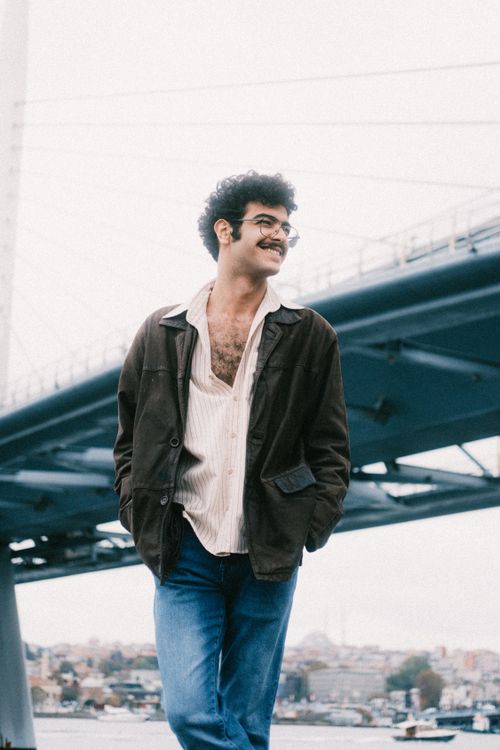 Free Casual man with a mustache walking near a bridge in an urban area. Stock Photo