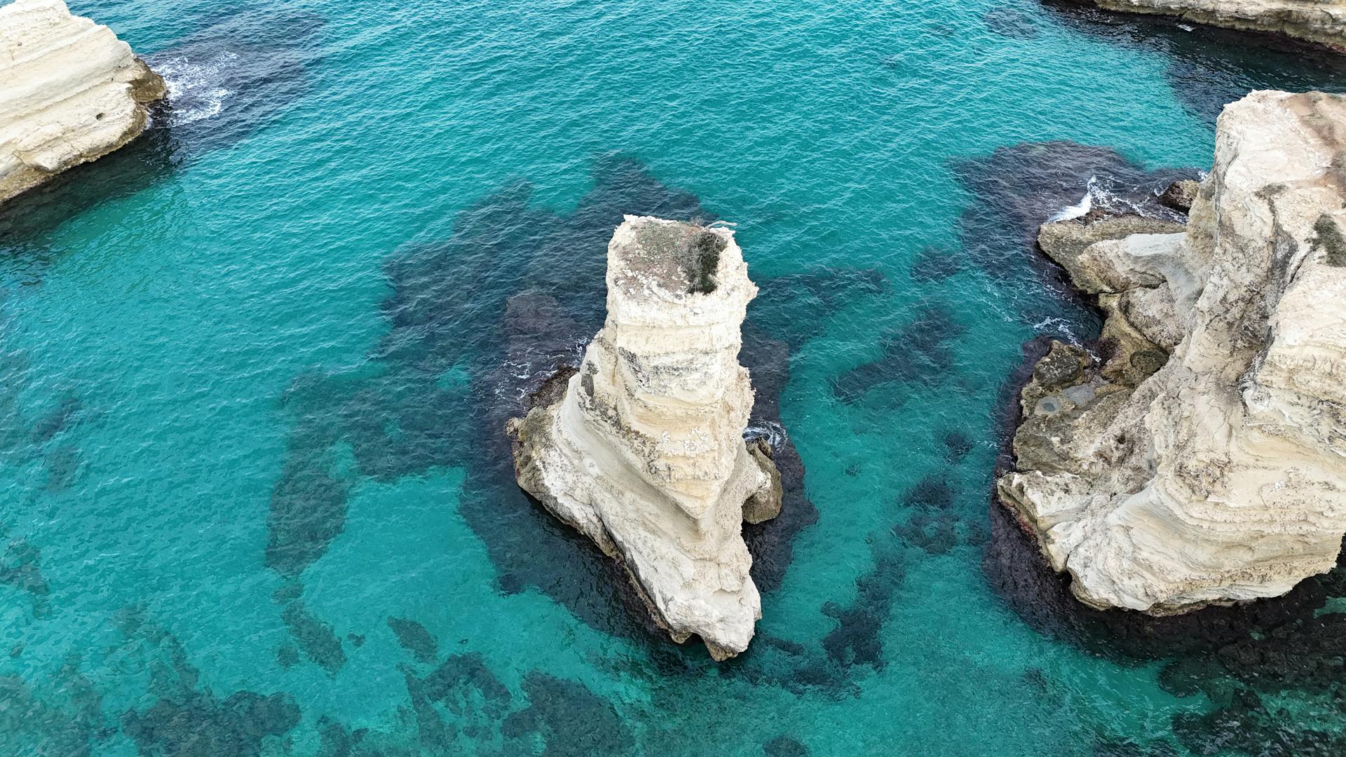 Stunning aerial shot of rugged limestone cliffs surrounded by vibrant turquoise sea.