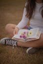 Young Woman Relaxing Outdoors with a Book and Flowers