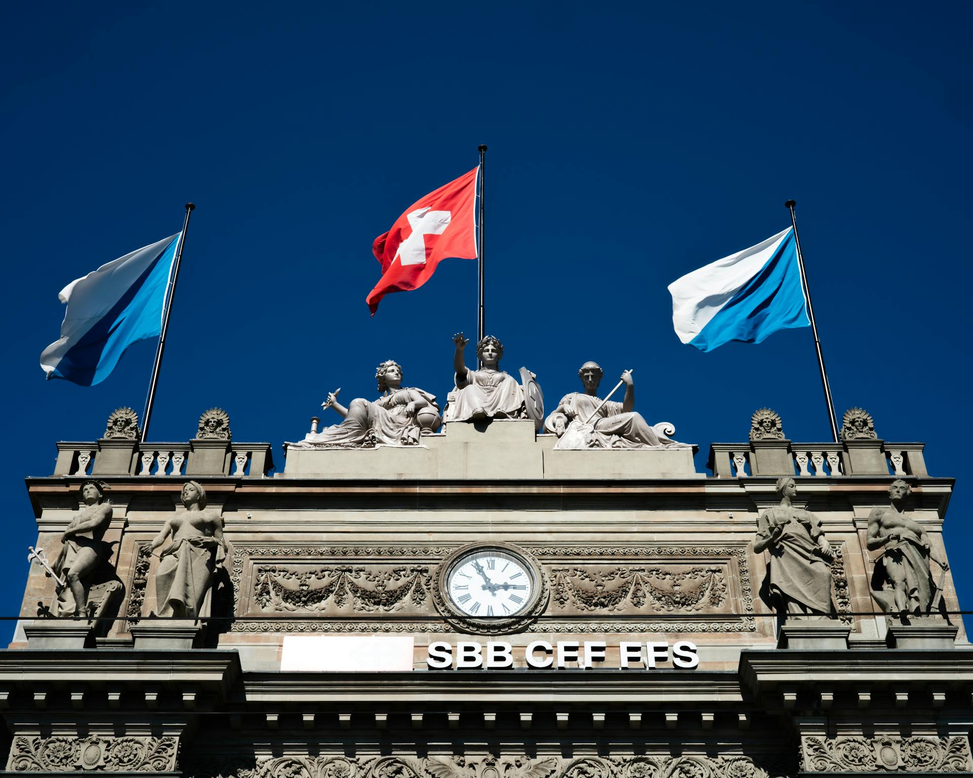 Historic SBB building with Swiss flags and sculptures in Zurich.