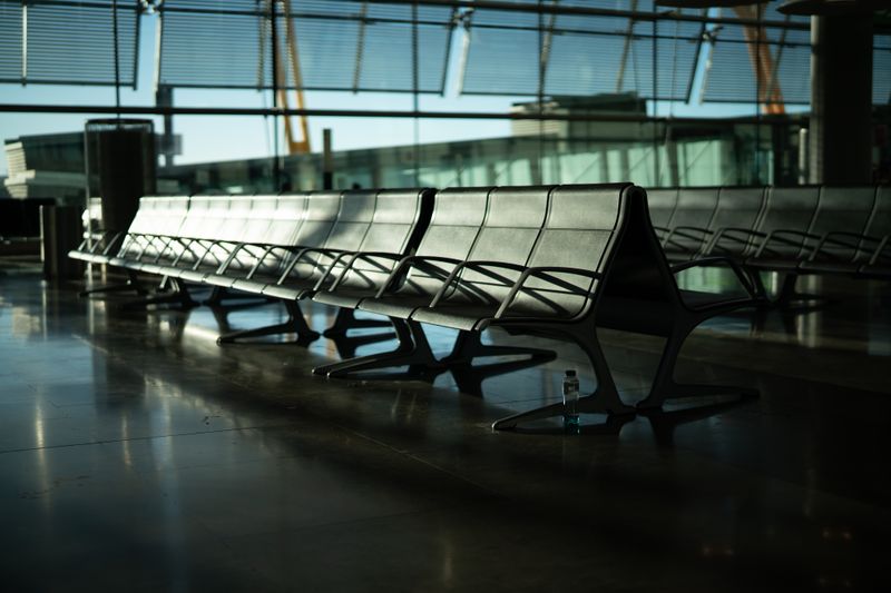 Deserted airport seating area with sunlight streaming through large windows. Calm and quiet atmosphere.