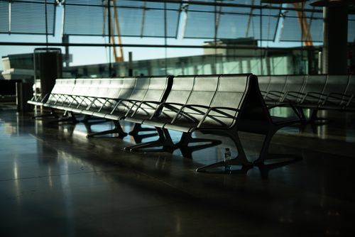 Free Deserted airport seating area with sunlight streaming through large windows. Calm and quiet atmosphere. Stock Photo