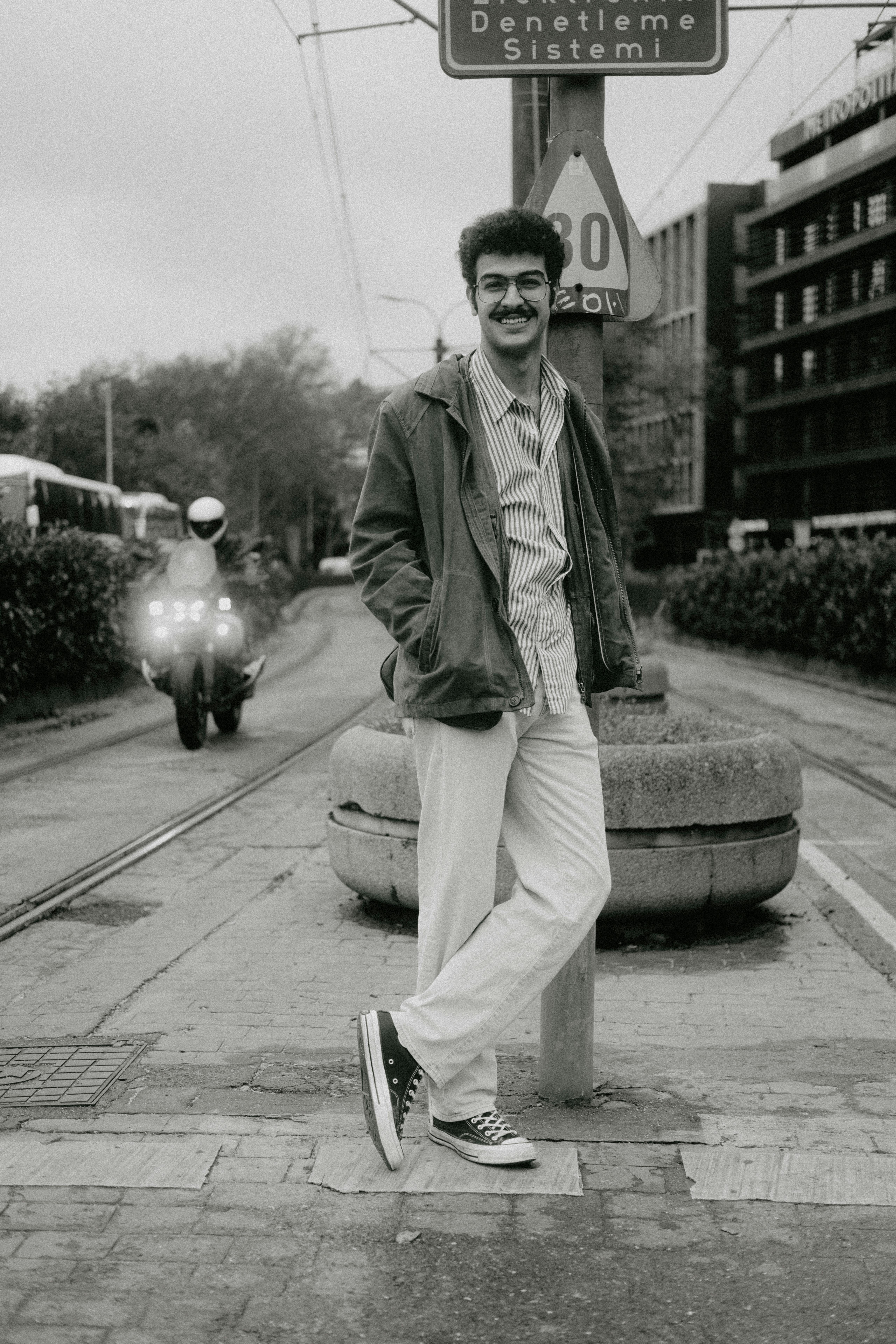 Black and white photo of a man posing in a city street with vintage vibes.