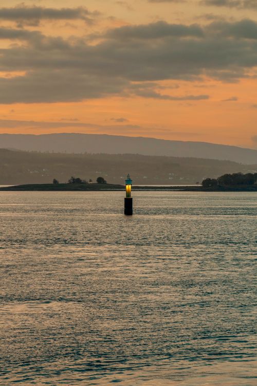 Free Serene early morning view of a lighthouse in Northern Norway with a tranquil fjord backdrop. Stock Photo