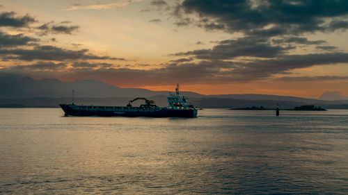 Free A cargo ship navigates calm waters at sunrise in northern Norway with mountains in the background. Stock Photo