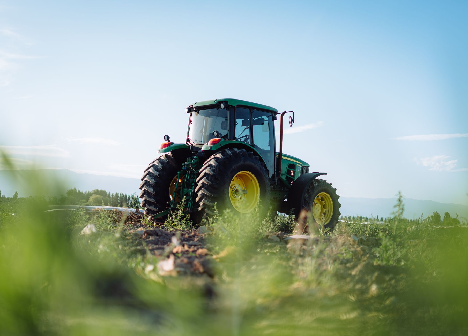 A tractor sits in a vineyard field under a clear sky in Mendoza, Argentina, highlighting rural agriculture.