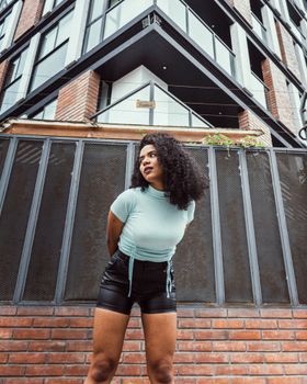 Confident woman posing in front of a modern building with urban architecture.