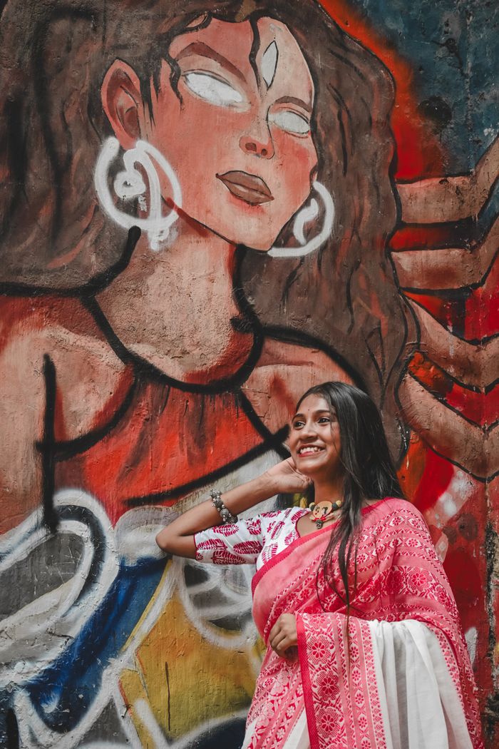 Woman in a pink saree beside painted graffiti