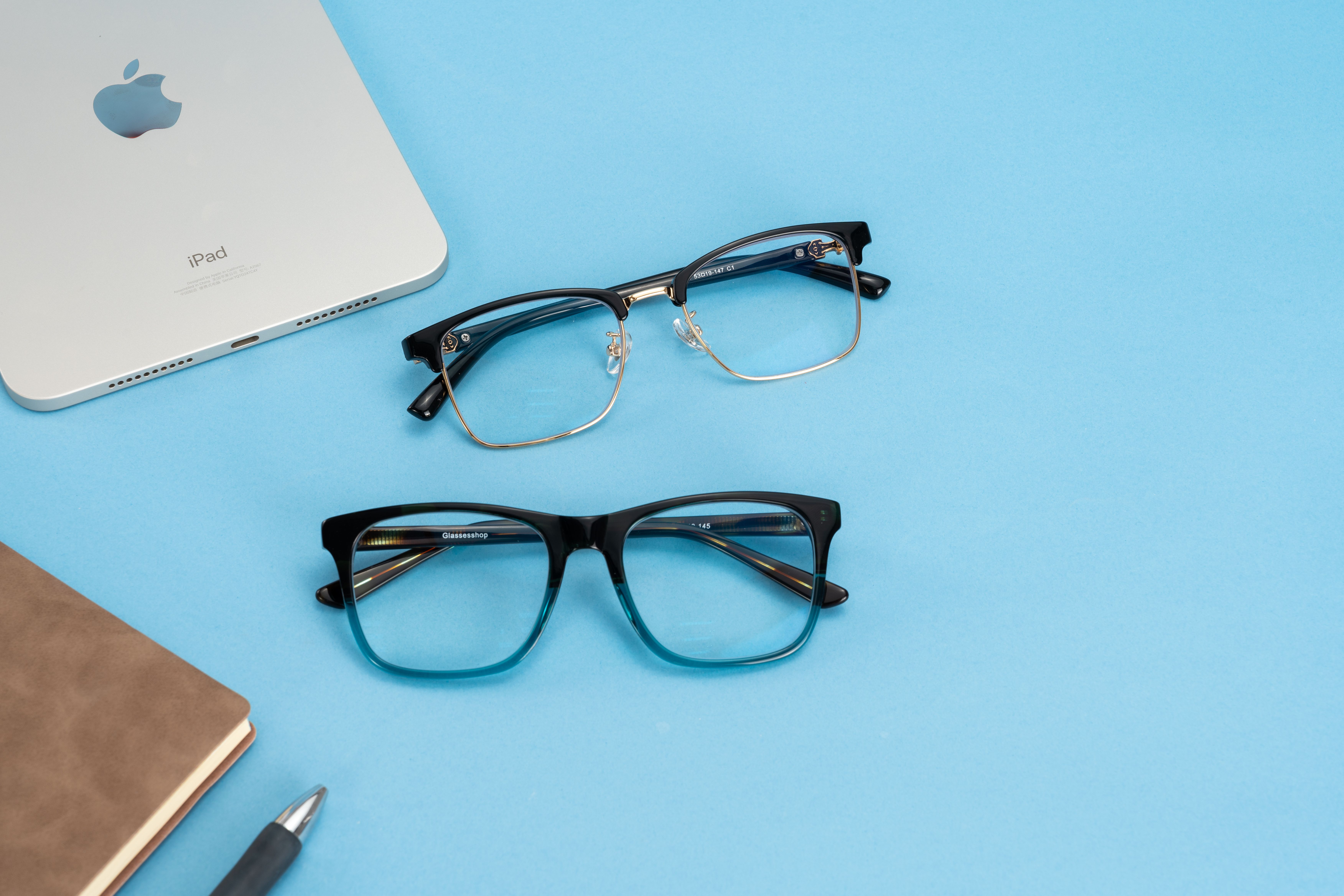 Stylish glasses and tech accessories arranged on a bright blue background, perfect for fashion and lifestyle themes.