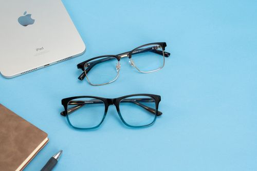 Free Stylish glasses and tech accessories arranged on a bright blue background, perfect for fashion and lifestyle themes. Stock Photo