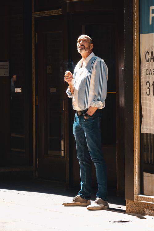 Free Middle-aged man standing outdoors smoking in sunlight. Stock Photo