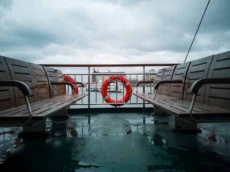 View from a ferry in Istanbul with wooden benches and lifebuoy on a rainy day.