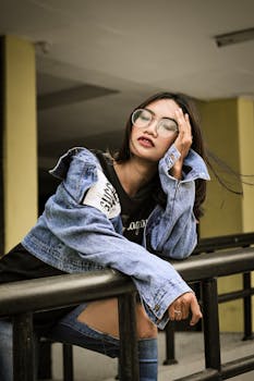 一位时髦的女士戴着眼镜，自信地在一件牛仔夹克上摆姿势