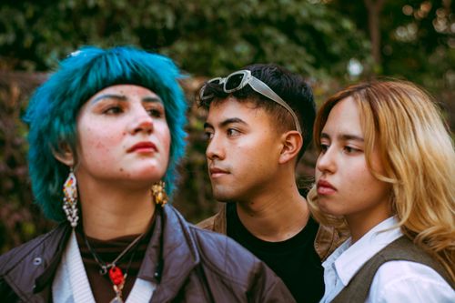 Free Three young adults express individuality with unique fashion in an outdoor setting. Stock Photo