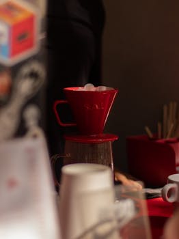 A red coffee dripper in a cozy cafe setup, capturing a warm and inviting atmosphere.