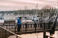 一名男子站在科纳凯码头的木制码头上，身后是游艇和港口