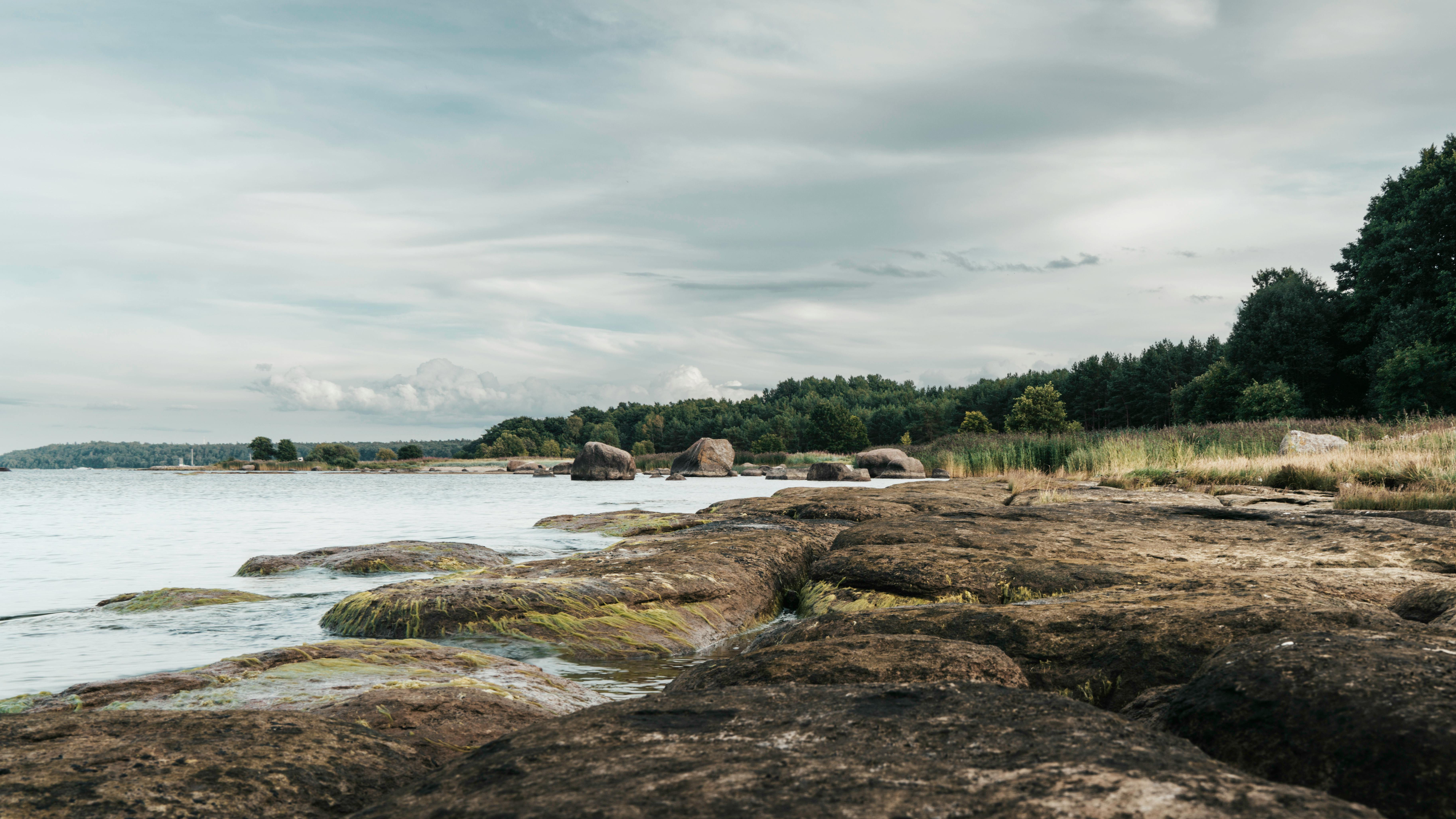 A serene untouched beach with rocky shorelines and a cloudy sky.