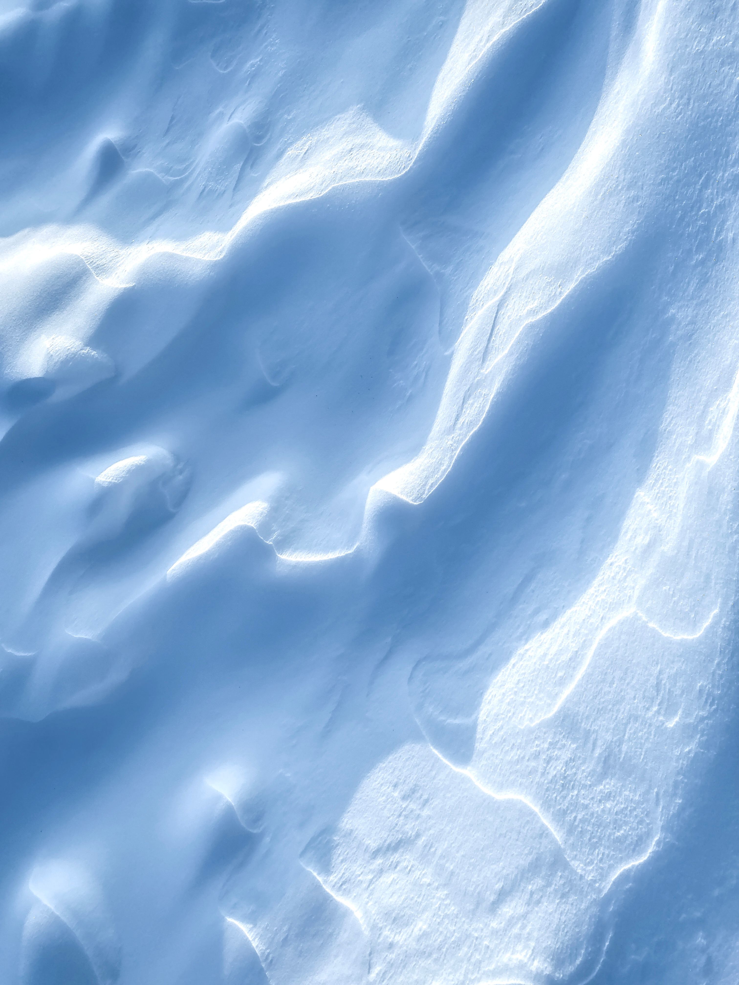 Free Elegant snow formations create abstract patterns with soft shadows. A serene winter scene with smooth textures. Stock Photo