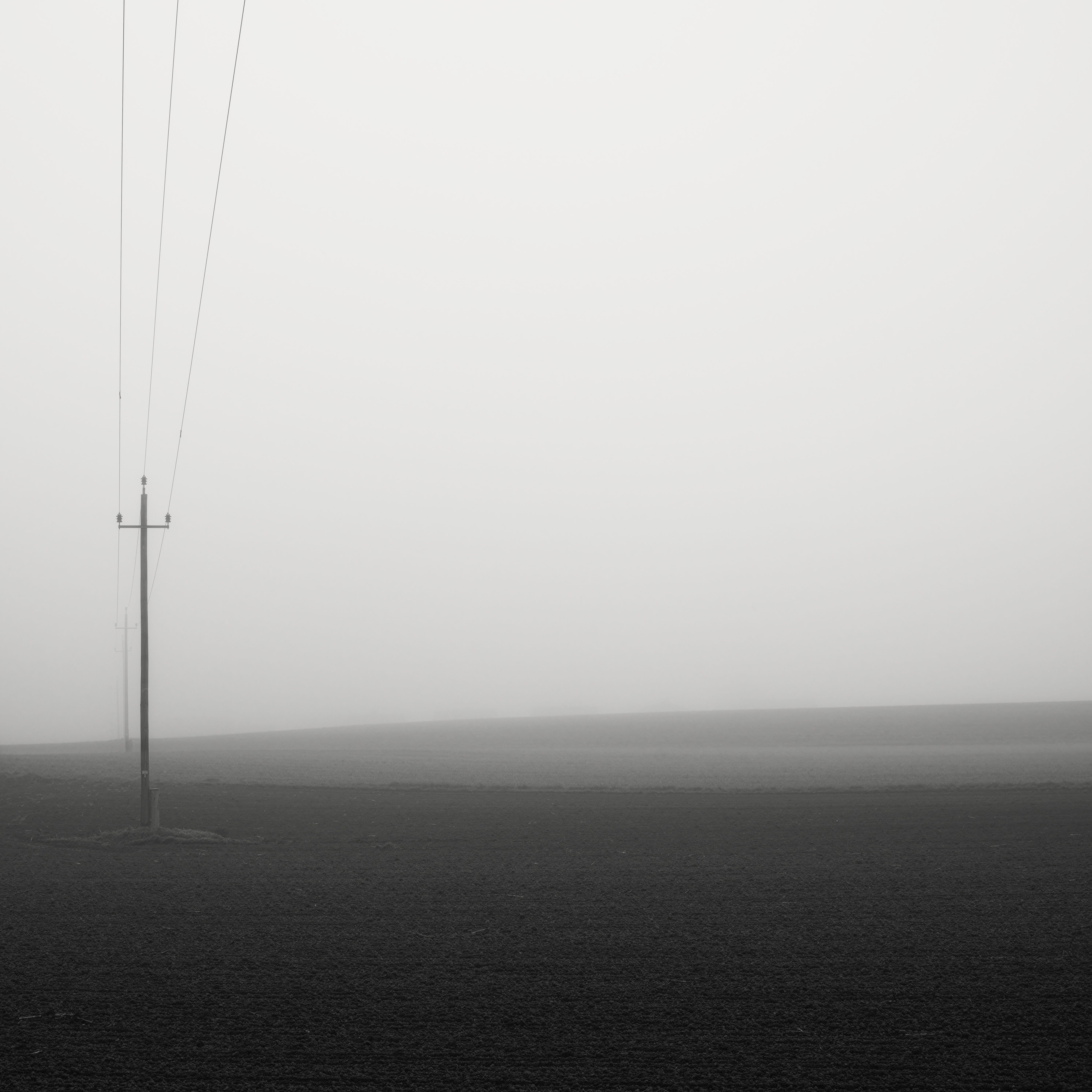 A minimalist foggy landscape with power lines in Pinsdorf, Oberösterreich.