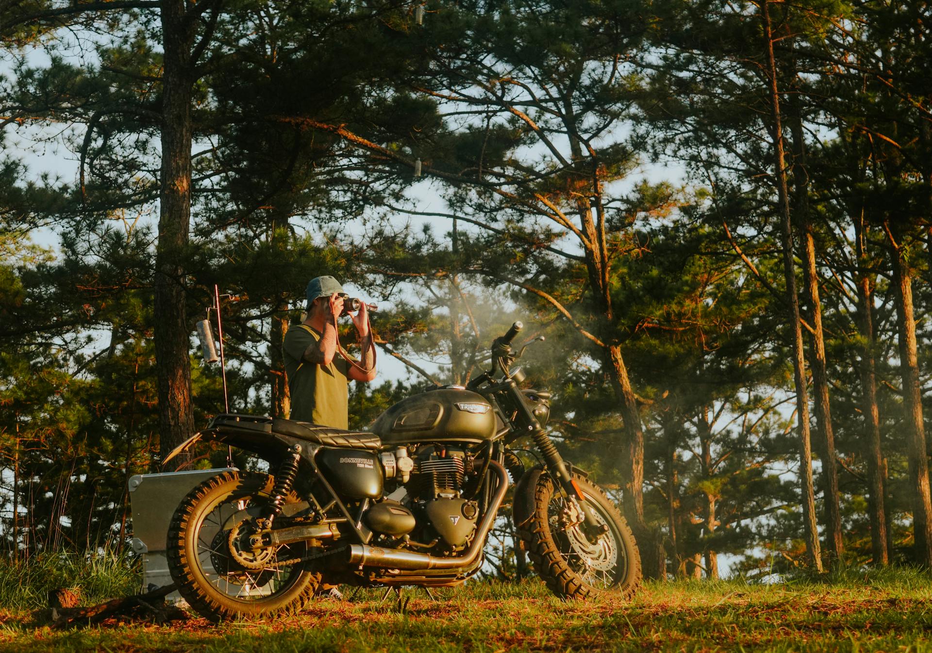 Motorcyclist with binoculars in a serene forest, capturing exploration essence.