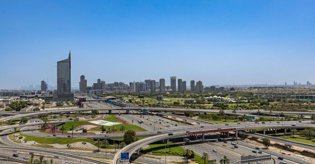 Aerial view showcasing Dubai's modern cityscape and highway network under a clear blue sky.