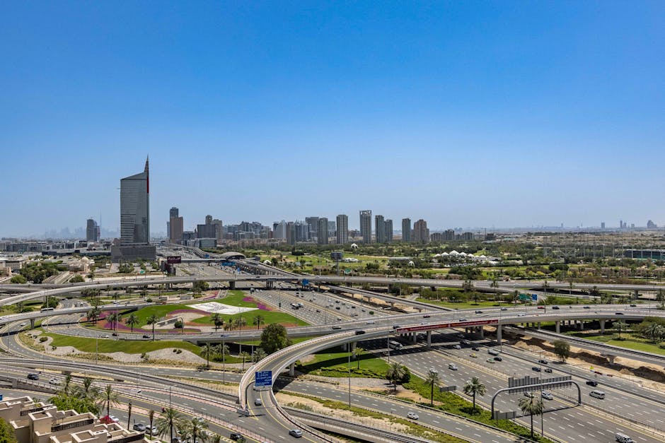 Aerial view showcasing Dubai's modern cityscape and highway network under a clear blue sky.