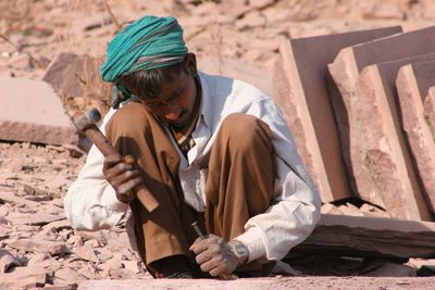 A stonemason chiselling a block by hand. Photo by Miguel Cuenca on Pexels