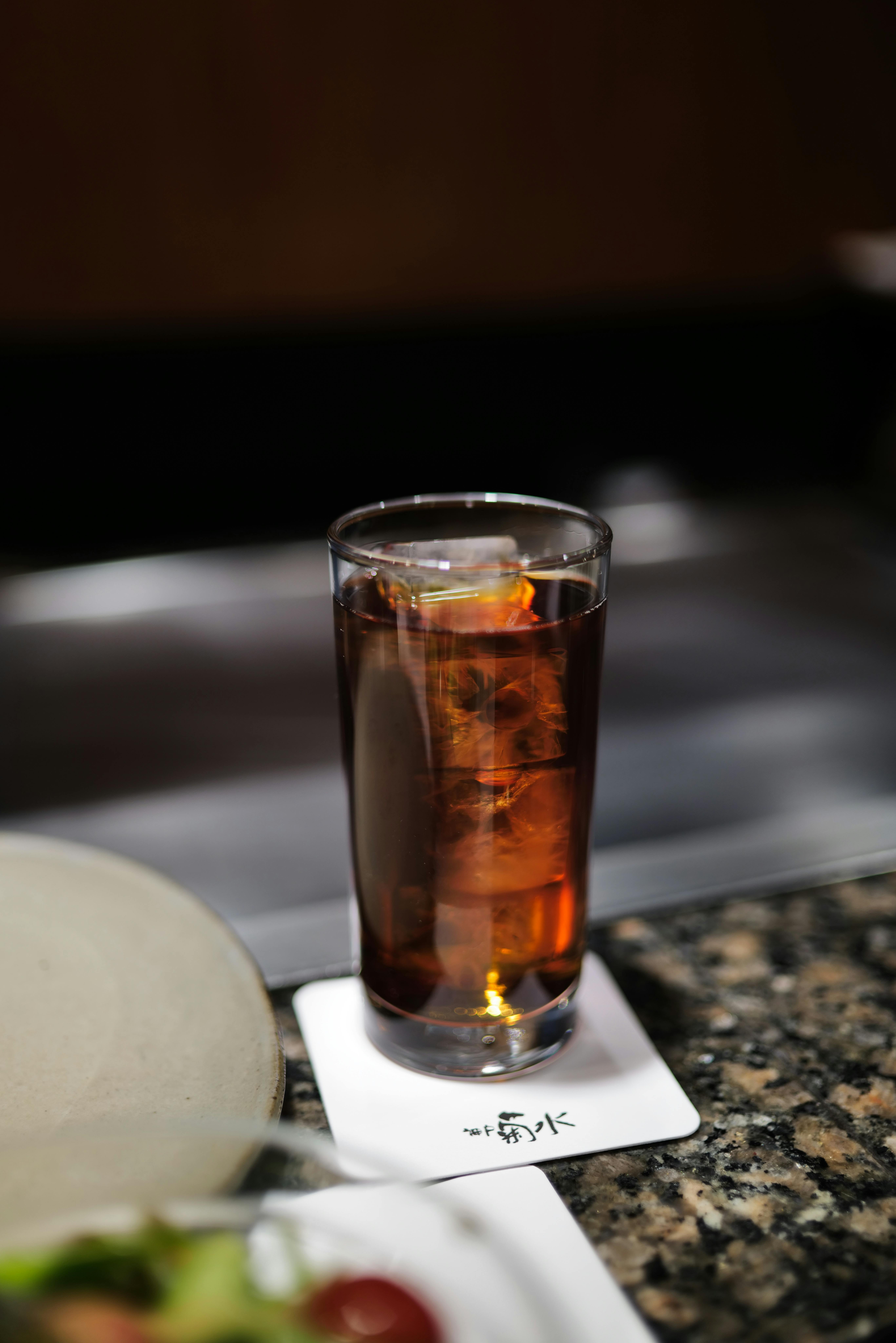 Chilled glass of iced tea with ice cubes on a marble counter, perfect for refreshment.