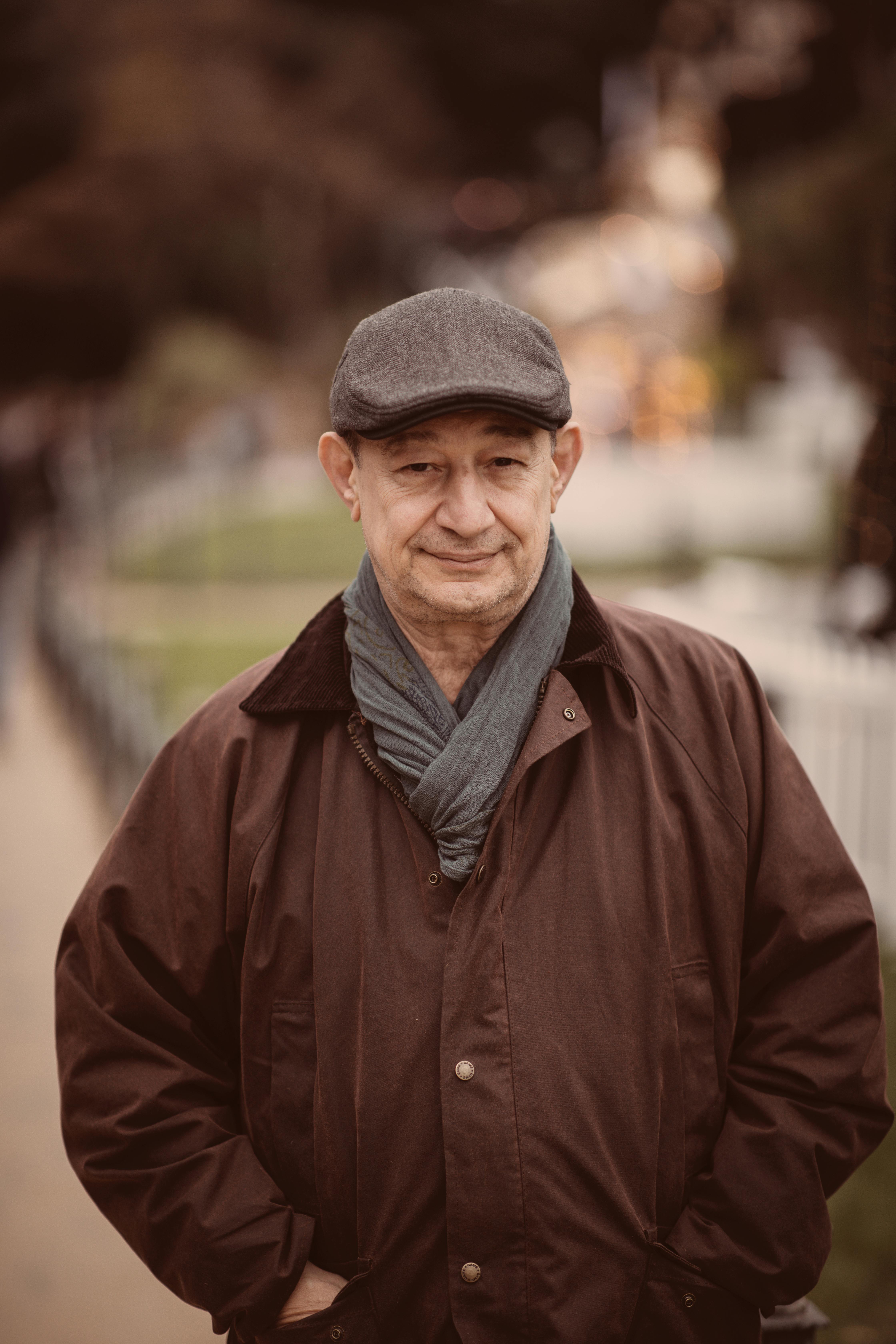 Senior man in a brown coat walking outdoors in Bournemouth, England on a cool day.