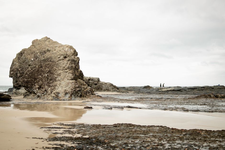 Scenic beach view with rocks and distant figures at Currumbin, Queensland.