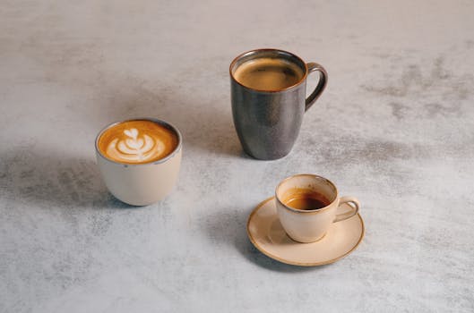 A variety of coffee drinks including espresso, latte art, and mug on a stylish table.