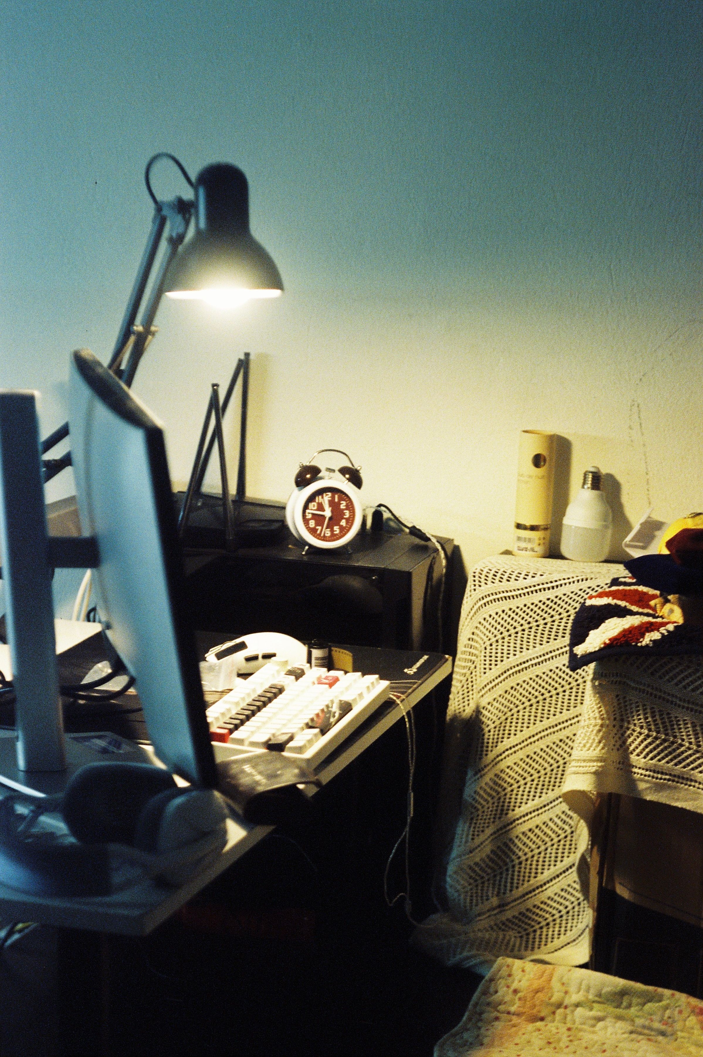 A cozy home office setup with a desk lamp, computer, and vintage clock for productive ambience.