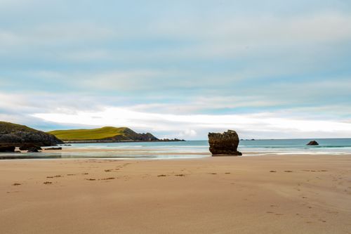 Free Serene beachscape with rock formations and distant hills under a clear sky. Stock Photo