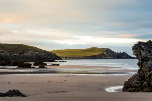 Free Serene coastal landscape featuring rocky islands and a sandy beach at dusk. Stock Photo