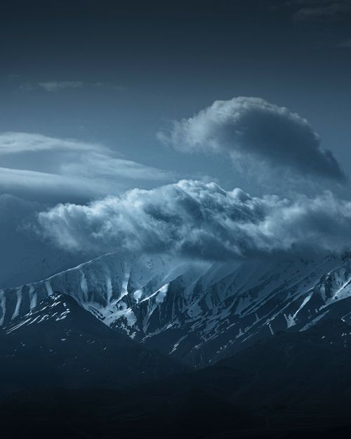 Free A striking view of snow-capped mountains enveloped by dramatic clouds, evoking a mysterious and moody atmosphere. Stock Photo