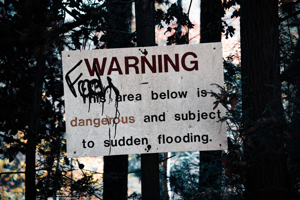 a warning sign about sudden flooding amid a forest setting emphasizing