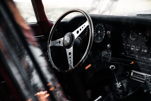 Close-up view of a vintage car interior featuring a classic steering wheel and dashboard.