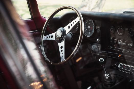 Close-up view of a classic car's steering wheel and dashboard, highlighting vintage style.