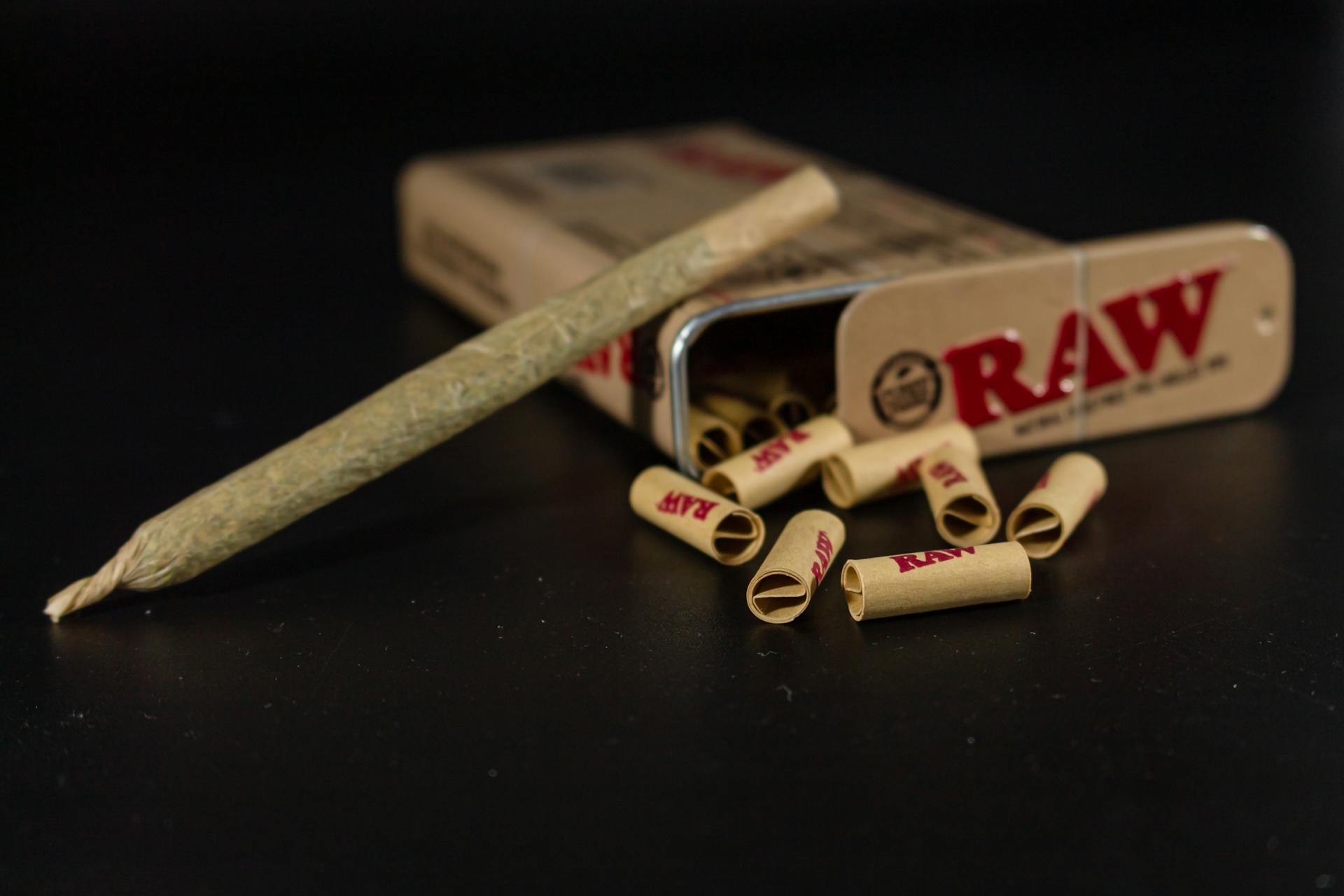 Raw rolling papers and a pre-rolled joint on a dark background, emphasizing smoking accessories.