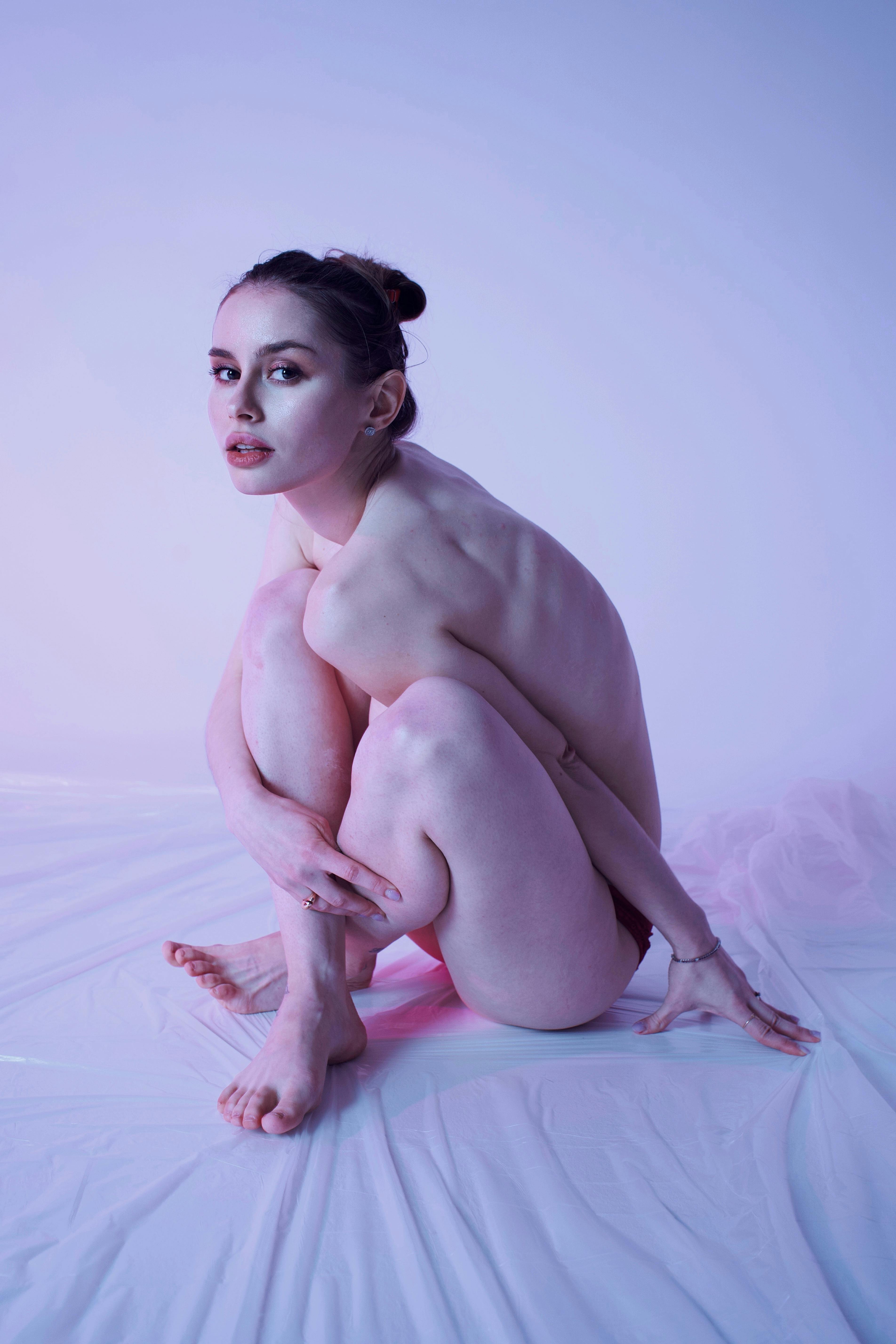 Sensual artistic nude form in soft lighting, woman reclined in dreamy pose, shadows and highlights accentuating curves and surrender