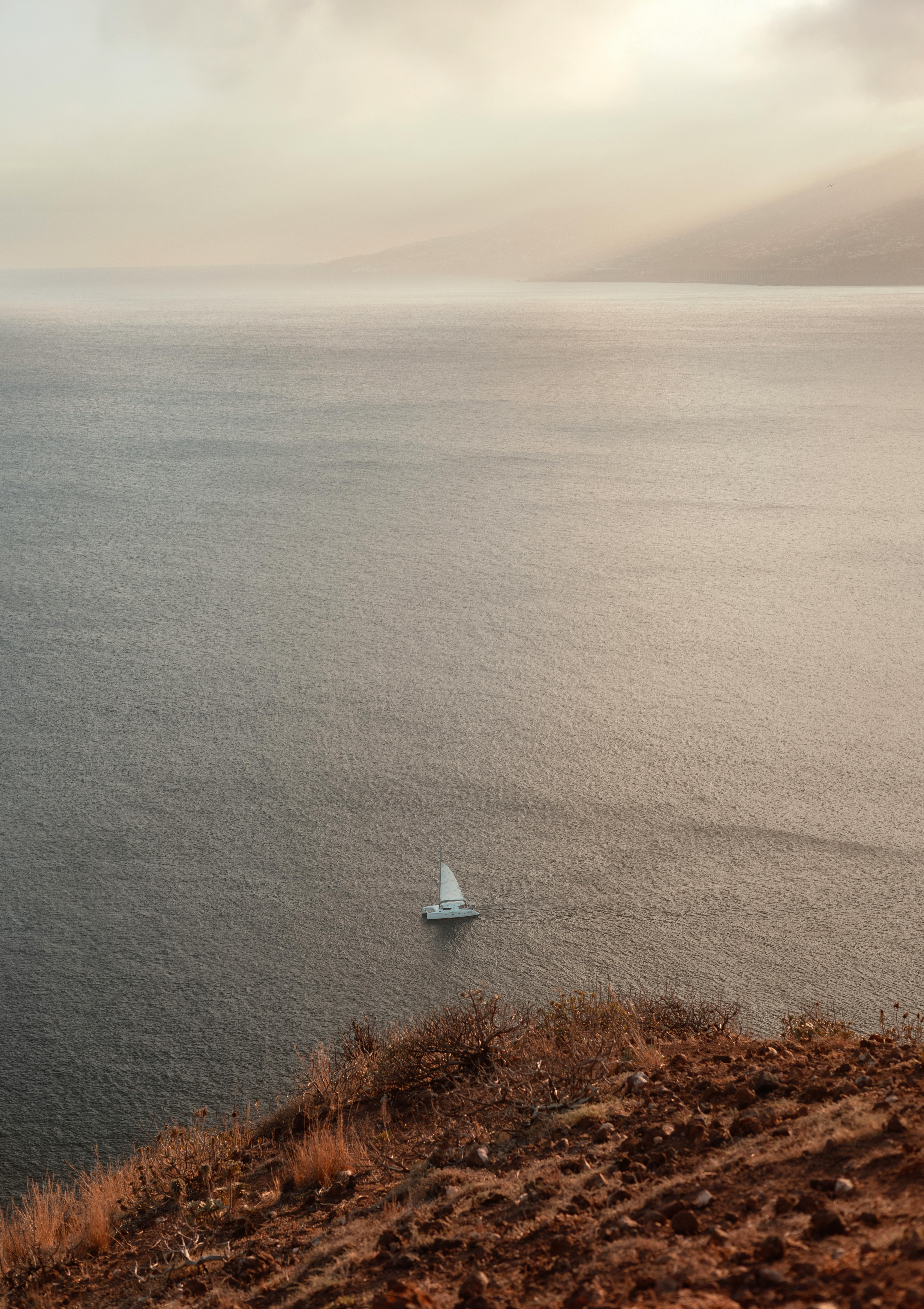 A tranquil scene featuring a lone sailboat navigating the calm waters near Madeira, Portugal.