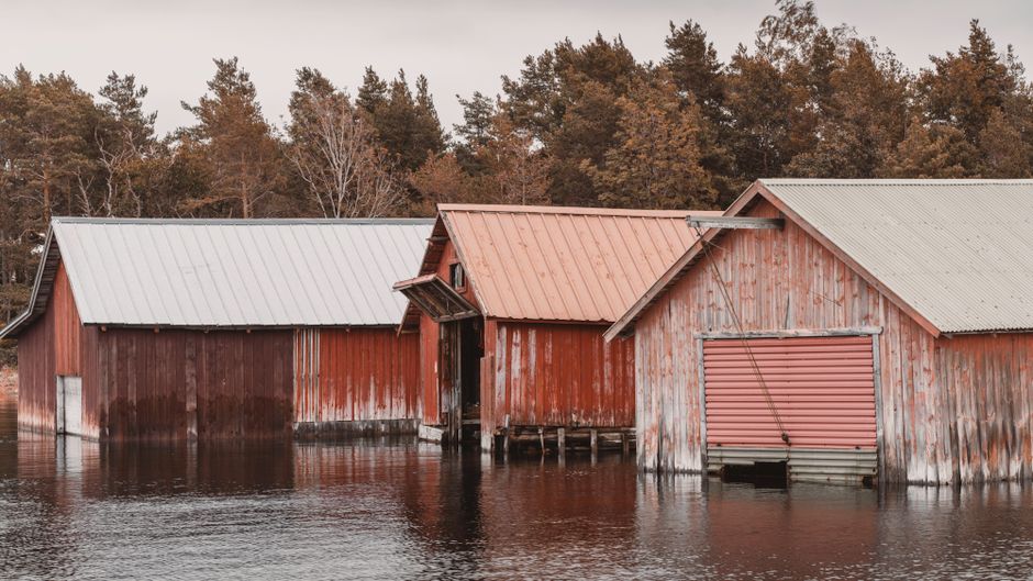 Rustic boat sheds on the serene shores of Åland Islands, Finland, reflecting a peaceful Nordic vibe.