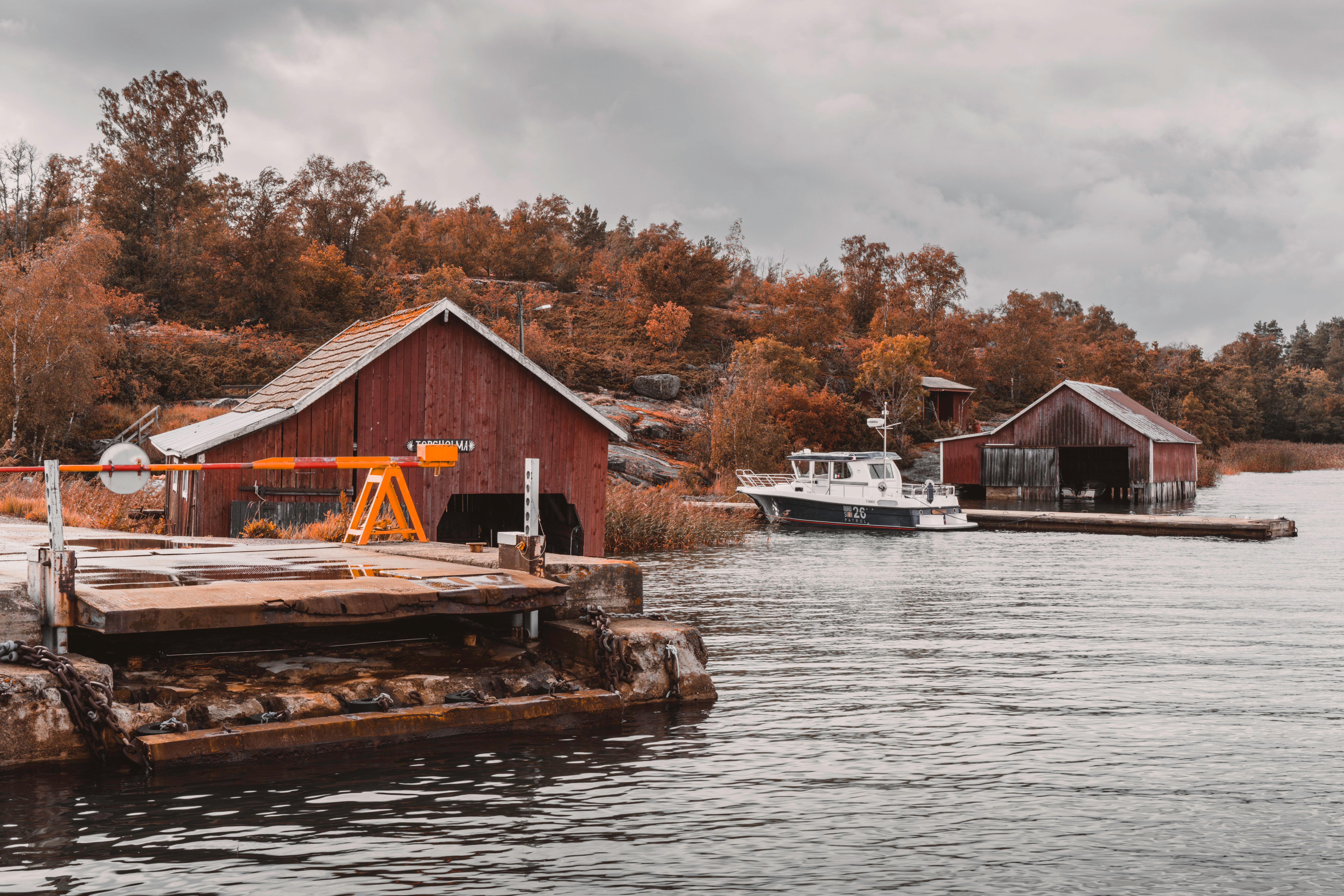 Picturesque autumn harbor scene with boat sheds and a ferry station in the Åland Islands.